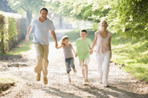Family running outdoors holding hands and smiling